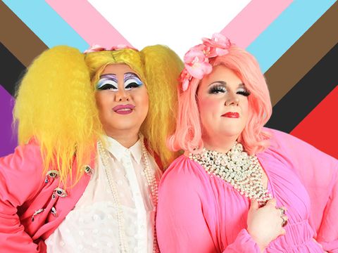 Zwei Drag Queens in Pink vor der Transgender-Flagge