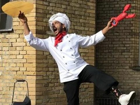 Als Koch gekleideter Clown jongliert mit Pizzaboden