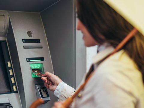 Woman holding a yellow umbrella while using the atm machine