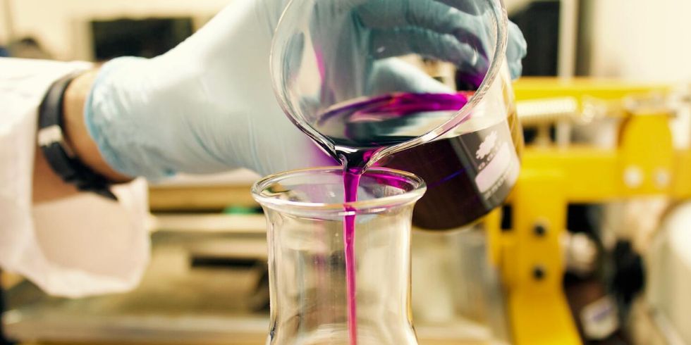 Eine chemische Flüssigkeit wird von einem Becherglas in ein Erlenmeyerkolben-Glas gefüllt.