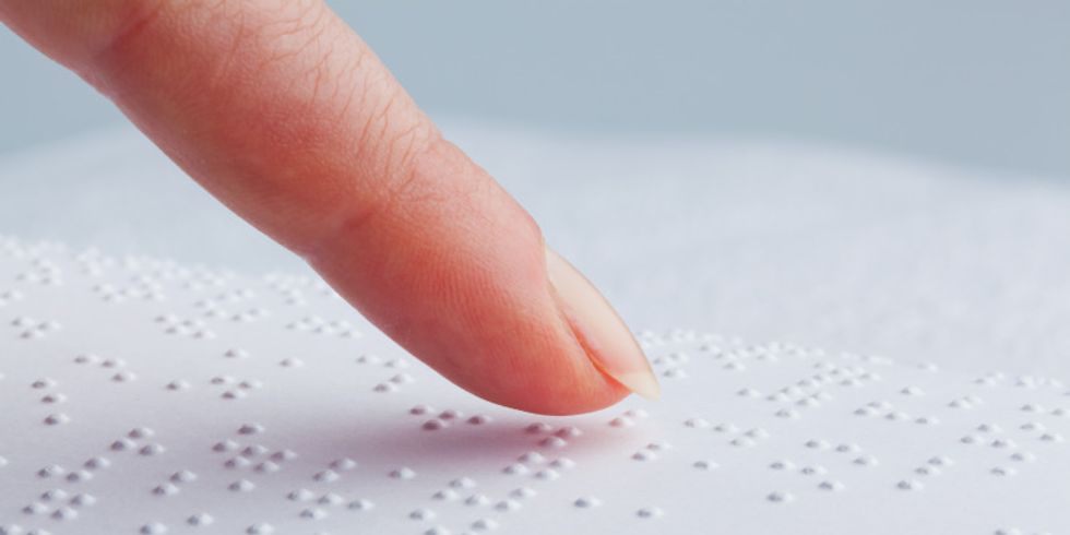 Zeigefinger fährt über Brailleschrift