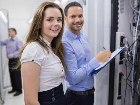 Zwei Personen stehen vor einem Server und lächeln