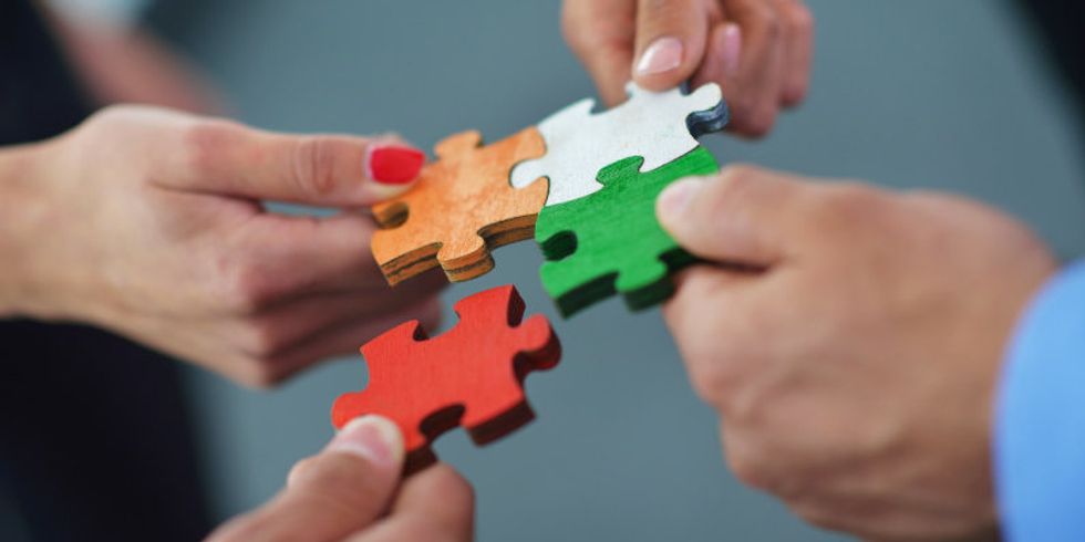 Hände stecken vier Puzzleteile zusammen