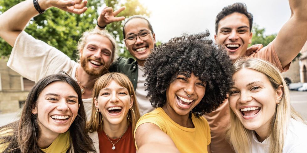 Multikulturelle Freunde, die draußen gemeinsam in die Kamera lächeln