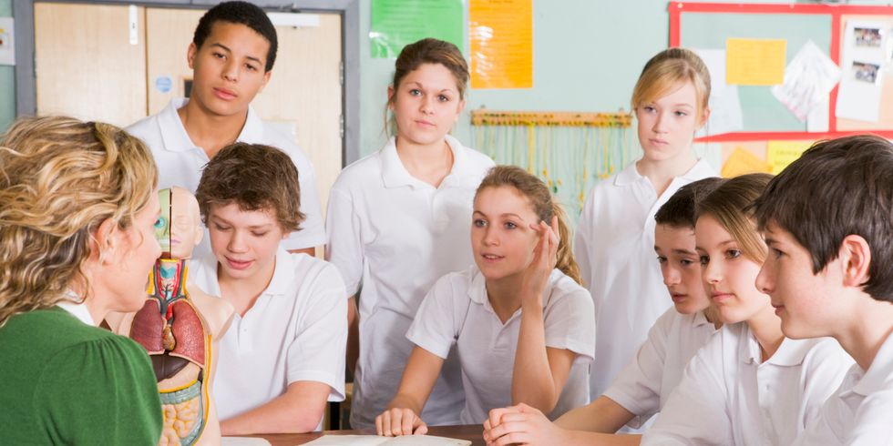 Schüler sitzen mit Lehrerin am Tisch