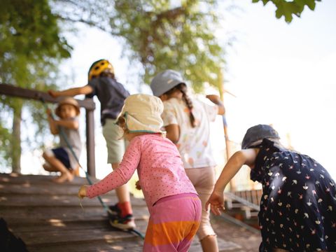 Kinder klettern Rampe an Holzspielplatz hoch