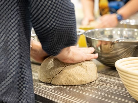 Eine Kursteilnehmerin knetet mit den Händen einen Brotteilg
