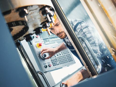 Arbeiter regelt am Bedienpult eine Maschine