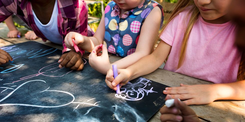 Kinder malen auf Tafel im Garten