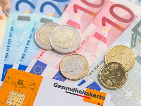 Auf verschiedenen Geldscheinen liegen Kleingeld und eine Krankenkassenkarte