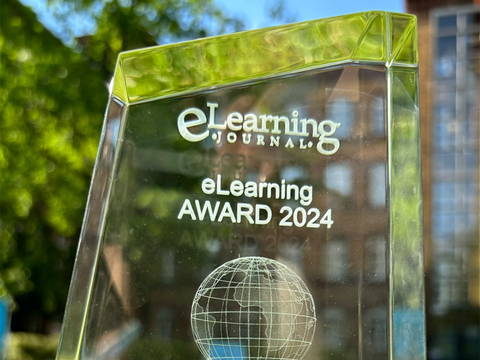 Der eLearning Award ist aus Glas und steht im Sonnenlicht vor der Verwaltungsakademie im Gras.