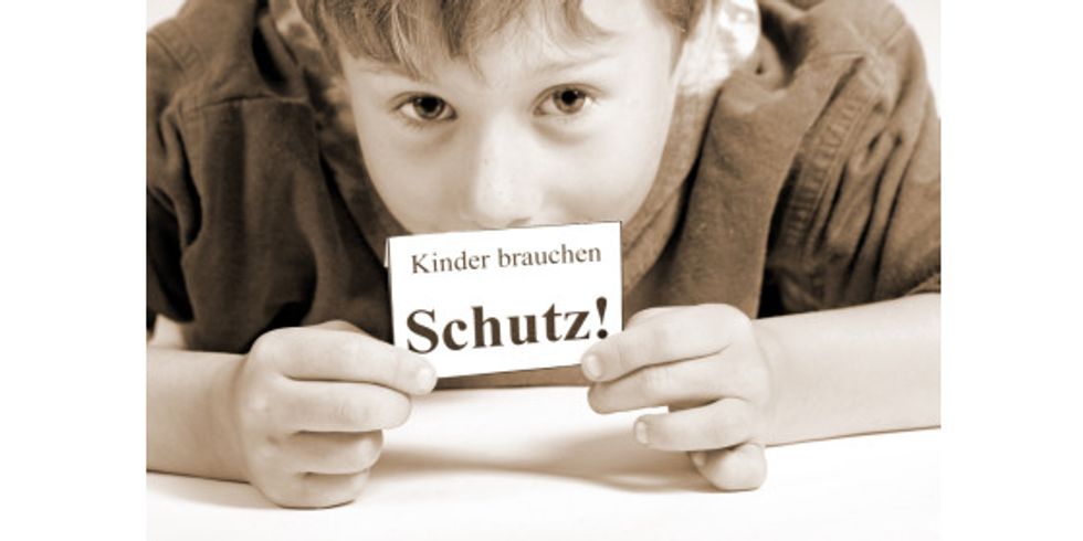 Junge mit Schild - Kinder brauchen Schutz