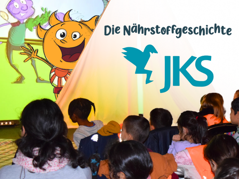 Mehrere Kinder in einem Theater, auf der Bühne sind Comicfiguren zu sehen