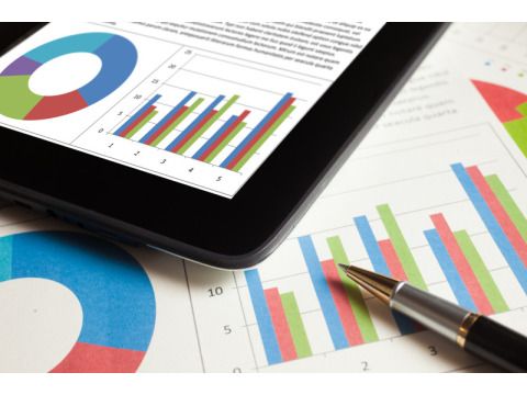 Statistische Aufbereitung auf Blatt mit Kugelschreiber und einem Tablet darüber liegend