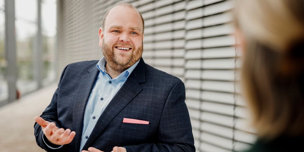 Ein Mann lächelt und schaut in die Richtung einer Person außerhalb des Bildes.