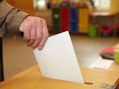 Stimmzettel wird in Wahlurne gesteckt