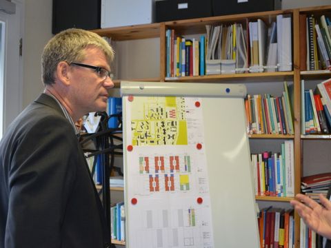 Bezirksbürgermeister Kleebank vor der Bauplanungsskizze für die neue Schule