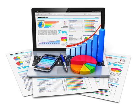 Laptopbildschirm, Smartphone und Papier mit Diagrammen liegen auf einem Tisch