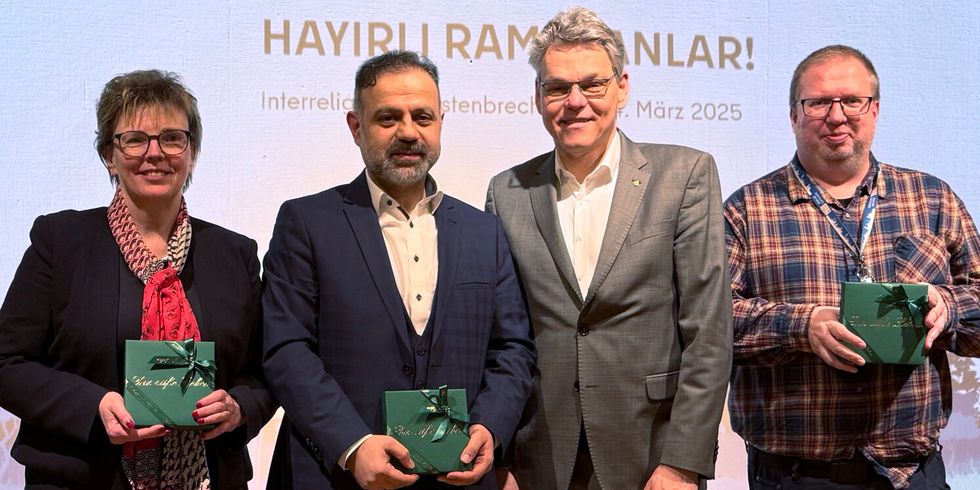 Ramadan Iftar Essen - eine Frau und drei Männer lächeln in eine Kamera und halten grüne Pralinenschachteln in der Hand