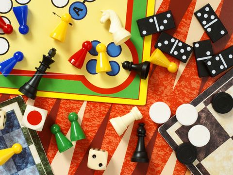 Blick auf ein Mensch ärgere Dich nicht-Spielbrett mit Fitguren, daneben Domino- und Damesteine