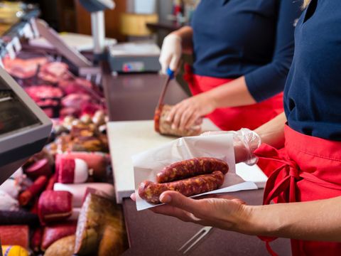 Verkäuferinnen in einer Metzgerei, die Fleisch und Wurstwaren verkaufen