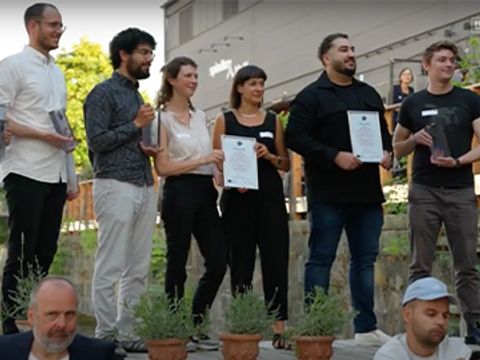 Gewinner:innen des DTA auf der Außen-Bühne mit Urkunden und Awards