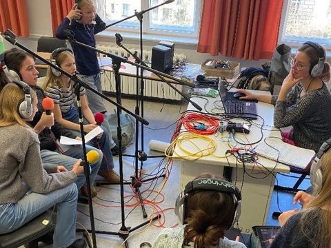 Sound On!: Kinder mit Kopfhörern und Mikrofonen machen eine Aufnahme für ein Hörspiel.
