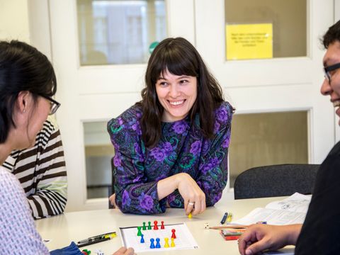 Vier Menschen spielen lachend ein Brettspiel