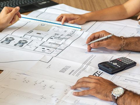 Ausgedruckter Plan für Hausbau, Hände daneben