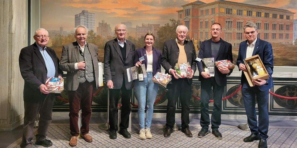 Sieben Personen, die für ein Foto posieren und Geschenke in den Händen halten