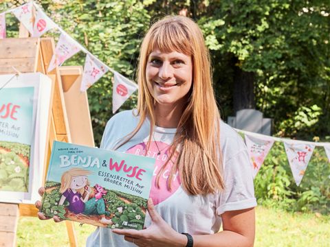 Wenke Heuts hält das Buch Benja & Wuse in den Händen und lächelt