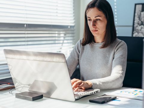 Frau arbeitet im Büro vor dem Laptop