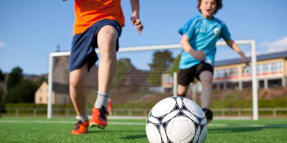 Jungs spielen Fußball auf Feld