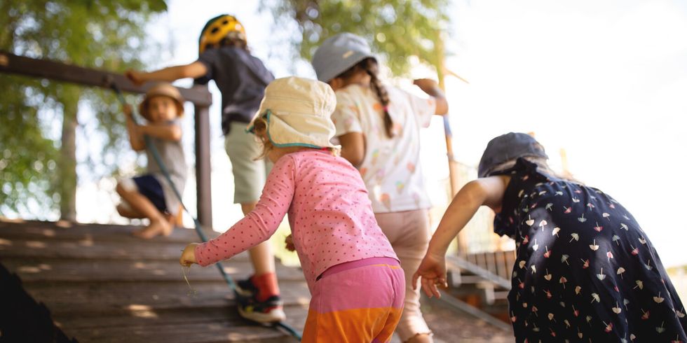 Kinder klettern Rampe an Holzspielplatz hoch