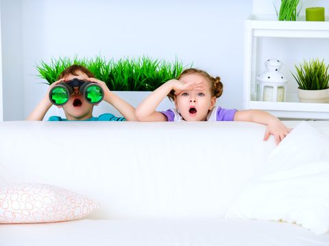 Zwei Kinder sitzen hinter einer Couch und entdecken etwas