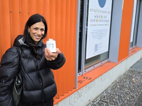 Zoe Naomi Hoffmann, Klimaschutzmanagerin in der OE Klima und Internationales, zeigt ein smartes Thermostat vor dem Gebäude in der Ohlauer Straße