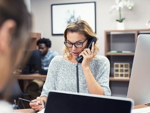 Frau sitzt am Tisch und telefoniert