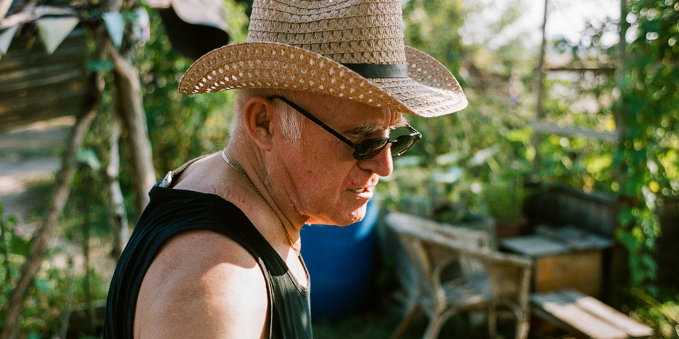 Ein Mann mit Sonnenhut und Sonnenbrille ist bei einem Arbeitseinsatz im Gemeinschaftsgarten.
