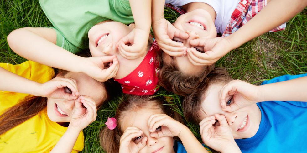 Im Kreis auf dem Gras liegende Kinder
