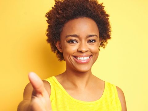 Lächelnde Frau streckt die Hand entgegen