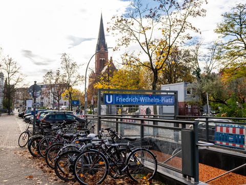 U-Bahn-Eingang mit Fahrradabstellplätzen, Kirche im Hintergrund.