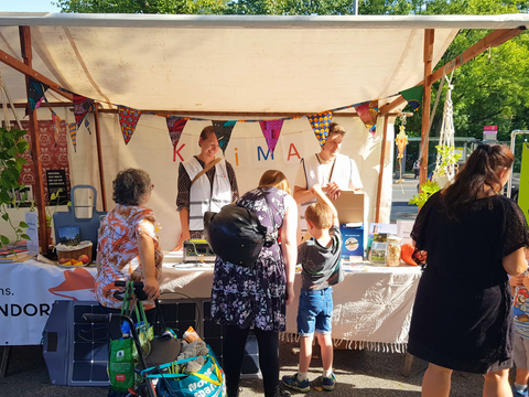 Das Bild zeigt einen Stand der Klimaleitstelle Reinickendorf. Davor stehen Menschen unterschiedlichen Alters und informieren sich im Gespräch mit den Mitarbeitern der Klimaleitstelle