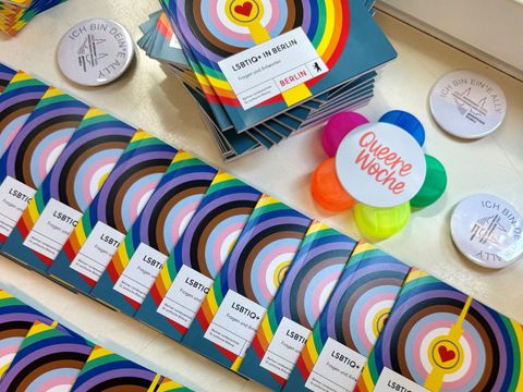 Das Foto zeigt Broschüren und Giveaways zur Queeren Aktionswoche im Bezirksamt Friedrichshain-Kreuzberg.