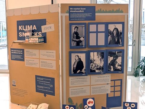 Eine Ausstellungswand zeigt viele verschiedene Bilder und Texte, zu lesen ist die große Überschrift "Klima Snacks"