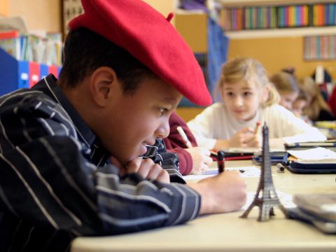 Junge sitzt am Schultisch mit Eiffelturm-Miniatur