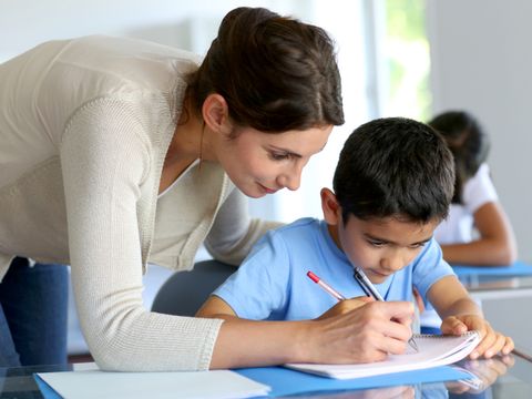 Lehrerin hilft kleinem Jungen bei den Hausaufgaben