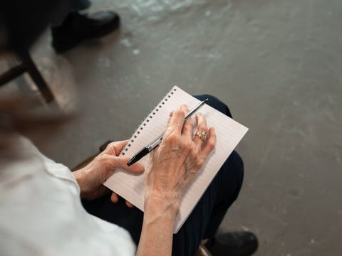 eine ältere Hand mit einem Schreibblock und Stift