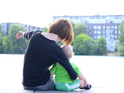 Mutter mit kleinem Kind in der Rückeansicht schauen auf Wohnhäuser.