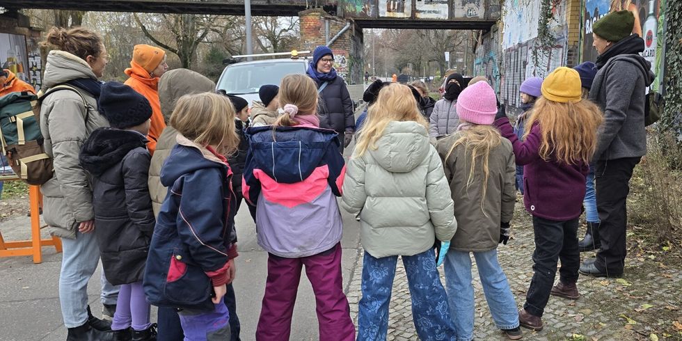 Bezirksstadträtin Annika Gerold (mi.) und die Umweltbildungskoordinatorin des Bezirksamts Katja Frenz (re.) besprechen mit den Schüler*innen der Fichtelgebirge-Grundschule die unterschiedlichen Wildblumen