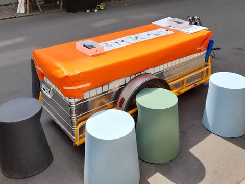 Fahrradanhänger als Arbeitstisch von Hockern umgeben